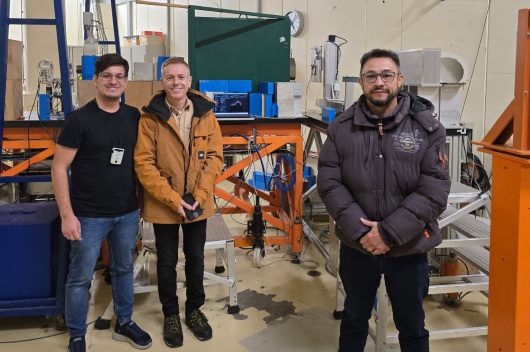 Professor da UFC,, Jarbas Silveira (dir.),, no Centro de Pesquisa em Terapia de Partículas (Partrec), nos Países Baixos. Lá, ele levou o projeto do nanossatélite cearense para realizar testes de radiação em um acelerador de partículas. Foto: Divulgação